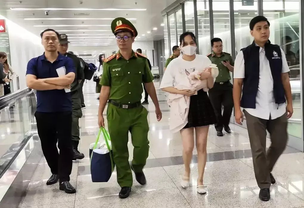 Ngô Thị Thêu bế con nhỏ bị dẫn giải về nước hôm 15/8/2025. Ảnh:Bộ Công an
